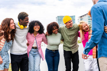 Happy playful multiethnic group of young friends bonding outdoors - Multiracial millennials students meeting in the city, concepts of youth, people lifestyle, diversity, teenage and urban life - DMDF09140