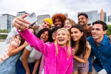 Happy playful multiethnic group of young friends bonding outdoors - Multiracial millennials students meeting in the city, concepts of youth, people lifestyle, diversity, teenage and urban life - DMDF09148