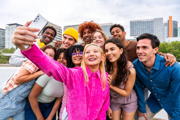 Happy playful multiethnic group of young friends bonding outdoors - Multiracial millennials students meeting in the city, concepts of youth, people lifestyle, diversity, teenage and urban life - DMDF09149