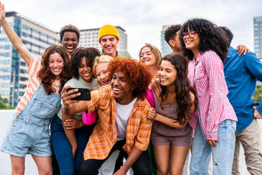 Happy playful multiethnic group of young friends bonding outdoors - Multiracial millennials students meeting in the city, concepts of youth, people lifestyle, diversity, teenage and urban life - DMDF09155