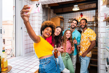 Multiethnic group of happy young friends having dinner barbecue party on rooftop at home - Multiracial cheerful young adult people having fun and bonding on a terrace balcony with city view, eating and drinking. - DMDF09173