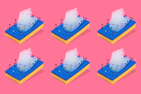 A creative representation of a blue and yellow scouring pads with colorful pins and bubbles of foam against a pink background - ADSF51194