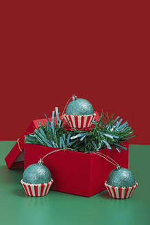 Sparkling turquoise Christmas ornaments nestled in red and white striped cupcake liners, presented in a festive red box - ADSF51195