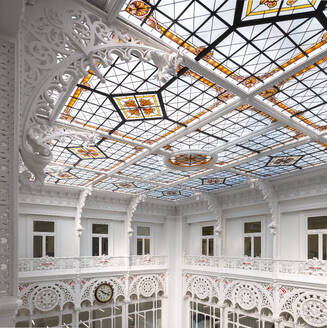 Low angle of skylight with stained glass design and carvings inside of large empty white library - ADSF51202