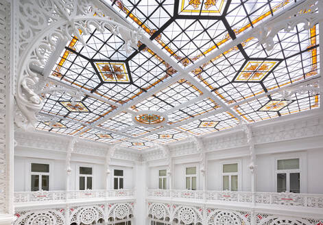 Low angle of skylight with stained glass design and carvings inside of large empty white library - ADSF51204