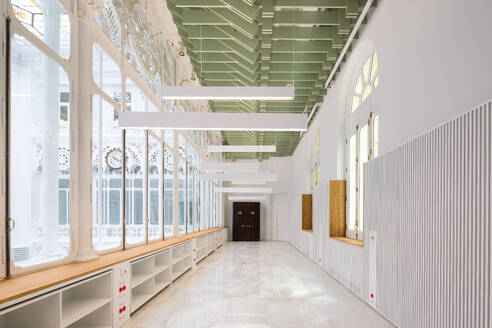 Empty long white corridor with racks below large windows and white walls in modern college library - ADSF51214