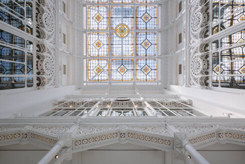 Directly from below view of large skylight with stained glass decor on white library with carvings - ADSF51219