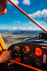 A pilot's hand is seen on the controls of a small aircraft, flying above a breathtaking landscape on a cloudy day - ADSF51225