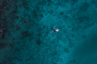 An aerial perspective captures a lone swimmer above the stunning, clear turquoise waters of Cancun's reef. - ADSF51230