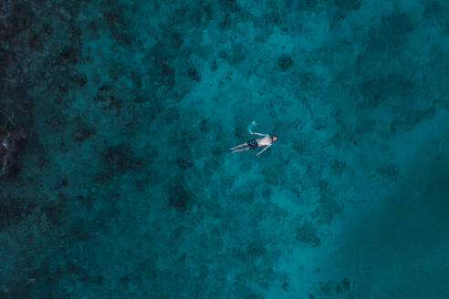 An aerial perspective captures a lone swimmer above the stunning, clear turquoise waters of Cancun's reef. - ADSF51230