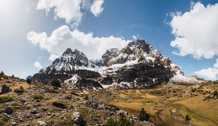 Panoramic view of snow-dusted mountains in Ordesa Valley, within Ordesa National Park in the Spanish Pyrenees, under a vast blue sky with clouds - ADSF51232