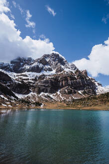 Scenic view of snow-capped Monte Perdido towering above a tranquil lake under a blue sky with fluffy clouds in Ordesa National Park, Huesca - ADSF51233