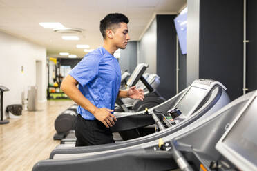 A young man in sportswear running in treadmill workout at a gym. - ADSF51302