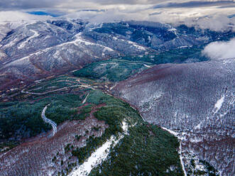 Drone view of majestic mountains covered with green coniferous trees and snow under clouds in countryside of Neila Spain Europe - ADSF51314