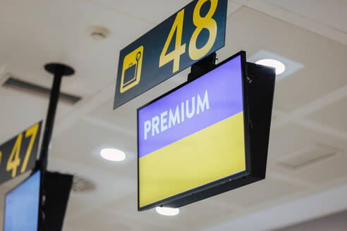 Illuminated 'Premium' check-in sign hanging at an airport counter for priority passengers - ADSF51374