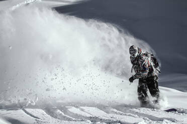 Full body of unrecognizable Snowboarder dressed in sportswear practicing snowboard mountain against cloudy sky during winter vacation on sunny day - ADSF51402