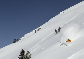 Unrecognizable active hiker dressed in sportswear practicing snowboard mountain against cloudy sky during winter vacation on sunny day - ADSF51404