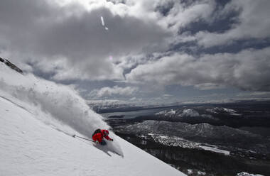 Full body of unrecognizable active person with skies jumping above snow covered mountain slope against cloud sky during winter vacation - ADSF51408