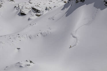 Aerial view of unrecognizable person snowboarding on snow covered mountain slope in Zermatt, Switzerland - ADSF51430