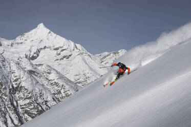 Full body of Anonymous Male Tourist snowboarding on majestic snow covered mountain slope against snowy rocky mountain under blue sky in Zermatt, Switzerland - ADSF51471