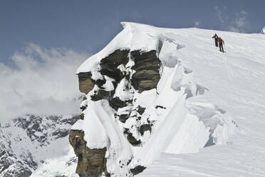 Back view of unrecognizable people climbing together on beautiful snow covered mountain slope at Swiss Alps during winter holidays - ADSF51478