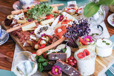 A vibrant gourmet charcuterie board filled with an assortment of cheeses, meats, and edible flowers. - ADSF51512