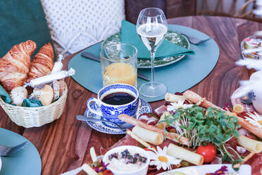 A well-appointed brunch table featuring a variety of foods including fresh croissants, cold cuts, and cheese, accompanied by coffee, juice, and wine. - ADSF51515