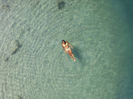 An aerial image showcasing a single individual blissfully floating in the crystal-clear turquoise waters of the Côte D’Azur in Nice, France. - ADSF51520