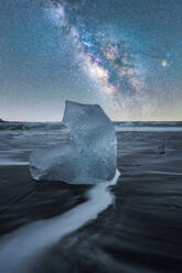 Majestic ice chunk on water under a starry sky at Diamond Beach, Iceland - ADSF51532