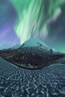 A majestic Northern Lights display over a snow-covered mountain in the serene landscape of Iceland, under a starry night sky. - ADSF51541