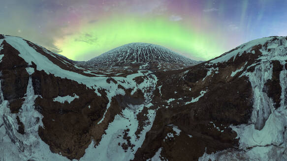 Enchanting aurora borealis illuminates the night sky above Iceland's snowy mountain peaks, providing a magical natural spectacle. - ADSF51545