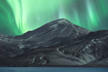 A mesmerizing display of the Northern Lights, or aurora borealis, illuminating the night sky above a majestic snow-covered mountain in the Icelandic wilderness. - ADSF51546