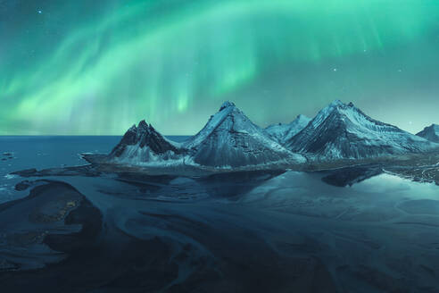 Majestic aurora borealis dances above the snow-capped mountains in the tranquil Iceland night sky. - ADSF51551