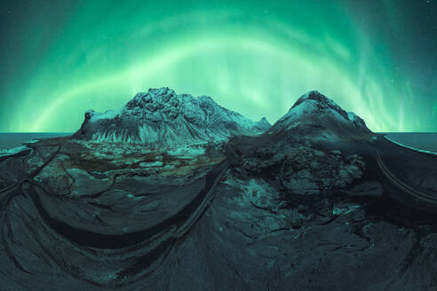 A stunning display of the Northern Lights dancing above the snow-capped mountains of Iceland under a starry sky. - ADSF51554