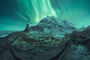 The breathtaking aurora borealis dances above a snow-covered mountain in Iceland, offering a display of nature's wonder under a starry sky. - ADSF51557