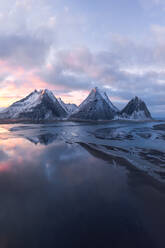 Snow-capped mountains reflected in tranquil waters under a pastel Icelandic sky. - ADSF51582