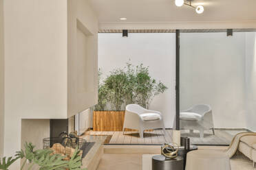 Patio with chairs and white wall and plant seen from living room window in contemporary apartment - ADSF51740