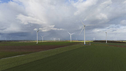 Windkraftanlagen auf einem Feld unter bewölktem Himmel - JCCMF11053
