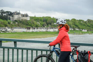 Frankreich, Centre-Val de Loire, Frau geht mit Fahrrad über die Brücke über die Loire - ANSF00684