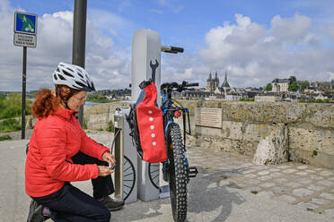 Frankreich, Centre-Val de Loire, Frau kniend an Fahrradstation - ANSF00688