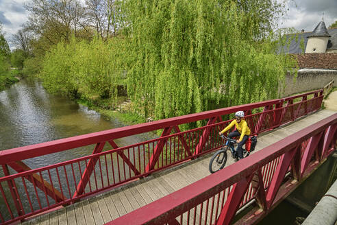 France, Centre-Val de Loire, Female cyclist riding across bridge - ANSF00689
