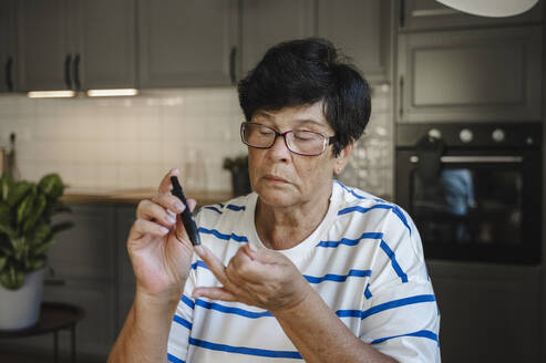 Ältere Frau sticht sich für Blutzuckertest in den Finger - ALKF00921