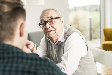 Älterer Mann im Gespräch mit seinem Enkel zu Hause - UUF30859
