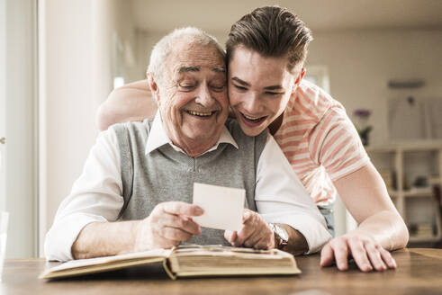 Happy grandfather and grandson looking at photographs together - UUF30868