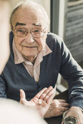 Grandson giving medicine to grandfather holding glass of water at home - UUF30872