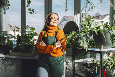 Contemplative botanist leaning on window sill in plant store - OLRF00015