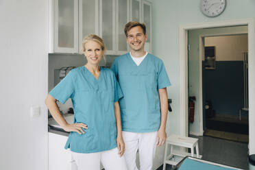 Portrait of smiling male and female animal experts standing in clinic - MASF41437