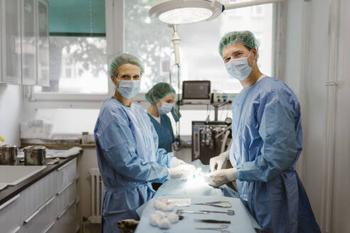 Portrait of male and female veterinarians in operating room at animal hospital - MASF41499