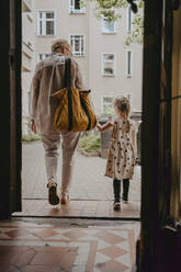 Senior woman walking with granddaughter seen through doorway - MASF41523