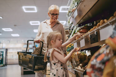 Side view of girl buying groceries with grandmother at store - MASF41527